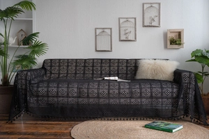 Close-up of black crochet lace sofa throw with floral cutout patterns and fringe edges