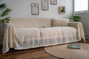 Macro detail showing beige crochet sofa throw with cotton tassel and bohemian patterns