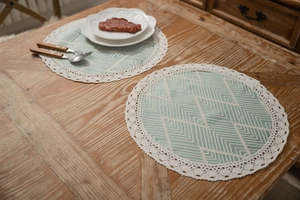 Close-up of green geometric jacquard round placemat with white crochet lace trim edge