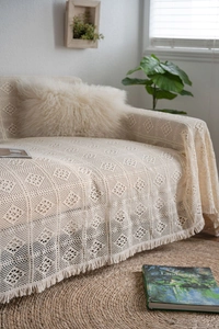 Detailed texture of bohemian beige cotton crochet sofa throw with decorative tassels