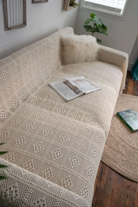 Close-up of beige knitted sofa cover featuring vintage geometric hollow crochet patterns