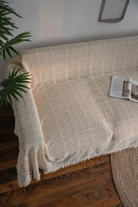 Detailed macro view of the cream crochet hollow throw with diamond patterns and tassels