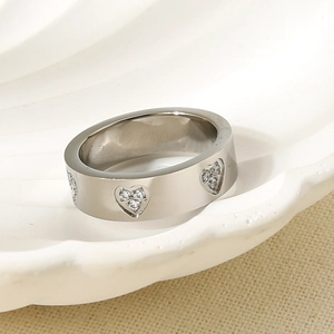 Detail shot of heart-shaped patterns and zircon inlay on a wide stainless steel ring