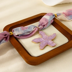 Dettaglio della collana in nastro di seta con pendente a stella marina in smalto