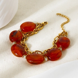 Gold-plated stainless steel bracelet with large red resin beads and white accents
