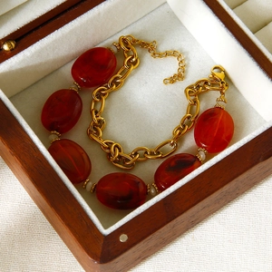 Detail of vintage bracelet with red amber-style beads and gold link chain in a box