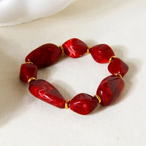 Detail of irregular dark red acrylic beads with gold spacers and marble texture