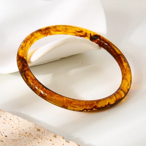 Détail d'un bracelet en résine ambrée avec texture marbrée sur un socle en pierre
