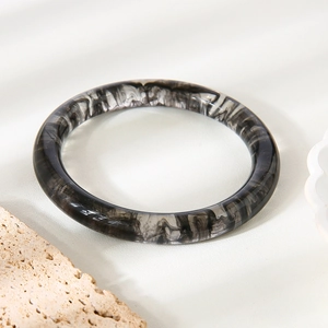 Détail d'un bracelet en résine avec texture marbrée d'encre noir et blanc sur pierre