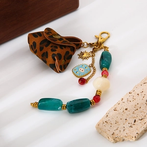 Détail de la pochette léopard et du pendentif œil maléfique sur un porte-clés doré