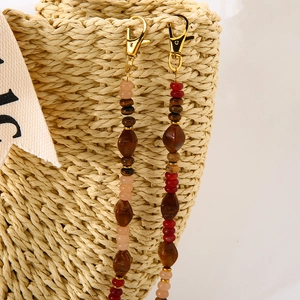 Detail of bohemian acrylic beads with golden lobster clasp on a straw bag