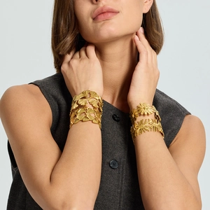 Detail of hollow ginkgo leaf and daisy patterns on 18K gold plated cuff bracelets