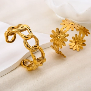 Detailed macro view of 18K gold-plated floral and textured chain open cuff bracelets