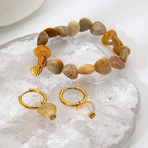 Detail view of natural stone heart earrings and beaded bracelet on glass prop