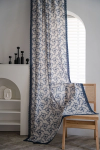 Detail of floral print curtain featuring blue flower patterns and navy lace edges