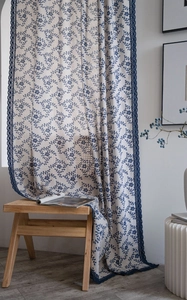Close-up of floral curtains with blue lace trim on textured cotton linen fabric