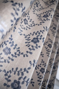 Close-up of vintage cotton-linen curtain fabric with navy floral pattern in beige