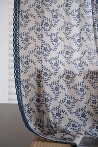 Close-up of floral print curtain with navy blue hand-crocheted lace edge detail