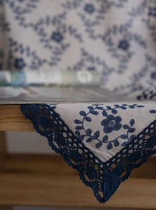Detail showing blue floral embroidery and deep blue hollow lace on beige cotton linen fabric