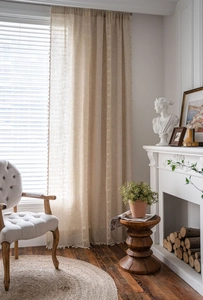 Detailed texture of beige linen curtain with crochet lace stitching and tassel fringe details