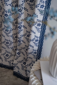 Detailed view of the blue floral print and intricate lace trim on the linen curtain