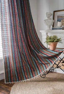Détail d'un rideau de style bohème en coton et lin avec des pompons à franges blanches