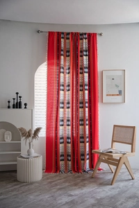 Detail of red Bohemian curtain with geometric patterns and white decorative tassels