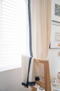 Detail of off-white curtain with elegant dark blue crochet lace trim and cotton linen texture