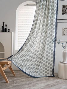 Détail du rideau à imprimé feuilles avec bordure en dentelle bleue et texture de lin