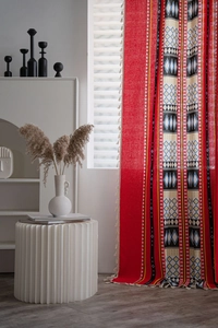 Detail of red Bohemian curtain with geometric patterns and white fringe tassels
