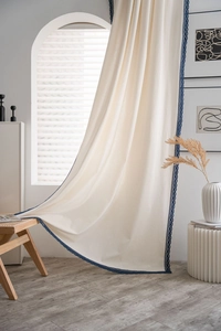 Close-up of white semi-shading curtain with navy blue lace trim and linen texture