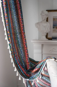 Détail du rideau bohème à rayures en coton et lin avec d'élégantes bordures à pompons
