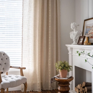 Rustic beige linen curtain with lace embroidery and tassel edges in a vintage living room