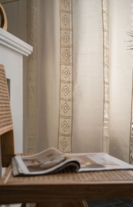 Detail view of beige linen curtain with intricate vertical crochet lace hollow-out patterns