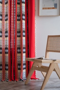 Detail of red Bohemian curtain featuring ethnic diamond patterns and white tassels