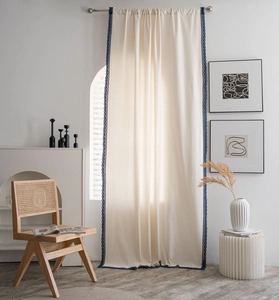 Detail of cream linen curtain featuring dark blue lace edge trim in a boho interior