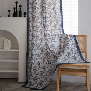 Floral print curtain with blue vine patterns and hollow lace trim in a rustic home setting