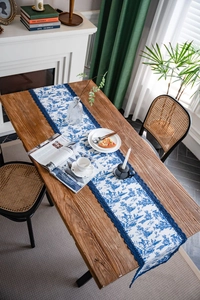 Détail d'un chemin de table aux motifs toile de jouy bleue avec bordures en dentelle