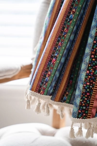 Détail d'un rideau bohème rayé en lin avec motifs colorés et pompons crème décoratifs