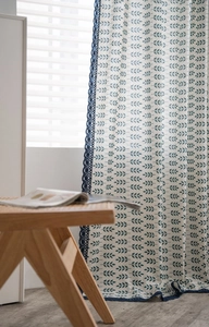 Détail du rideau à motif de feuilles vertes avec bordure décorative en dentelle bleue