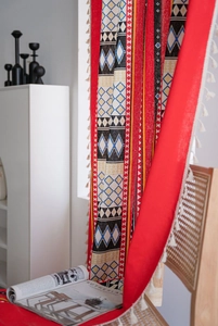 Detail showing bohemian red textile with geometric patterns and fringe on a rattan chair