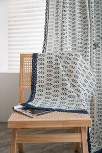 Détail du tissu à motif de feuilles avec dentelle bleue sur une chaise en bois