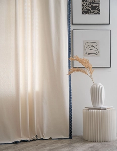 Detail of cream linen curtain featuring elegant navy blue lace crochet border trim