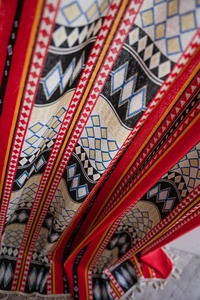 Detailed macro view of Bohemian red fabric featuring geometric diamond patterns and white tassels