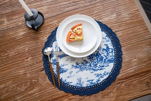 Détail de set de table bleu et blanc à motif pastoral avec bordure en dentelle crochet