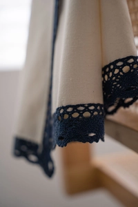 Close-up of cream linen curtain fabric with dark blue hollow crochet lace edge detailing
