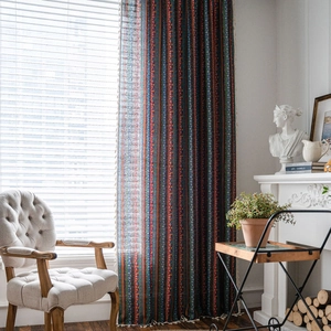 Bohemian striped linen curtains with white tassel trim hanging in a warm living room scene