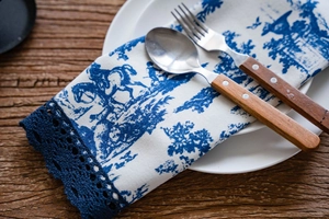 Détail de la bordure en dentelle bleu foncé et de l'imprimé champêtre sur le chemin de table