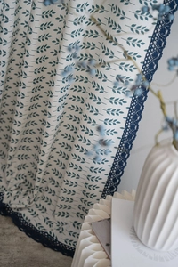 Détail du rideau à imprimé feuilles avec bordure en dentelle et tissu en lin
