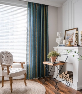 Detail of Bohemian curtain with blue yellow stripes and white tassel trim on cotton linen
